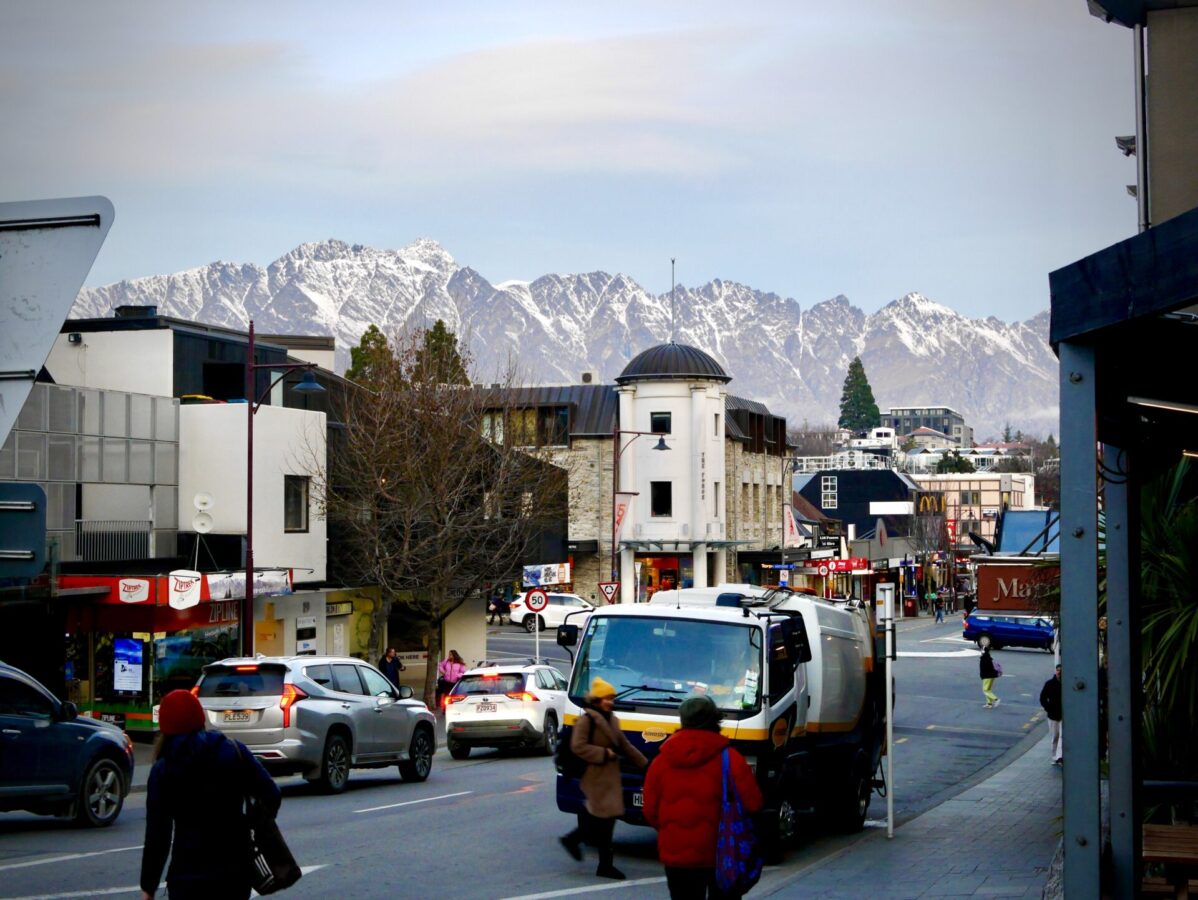 Busy downtown Queenstown, NZ, with the snowy Remarkables Mountain Range in the backdrop.