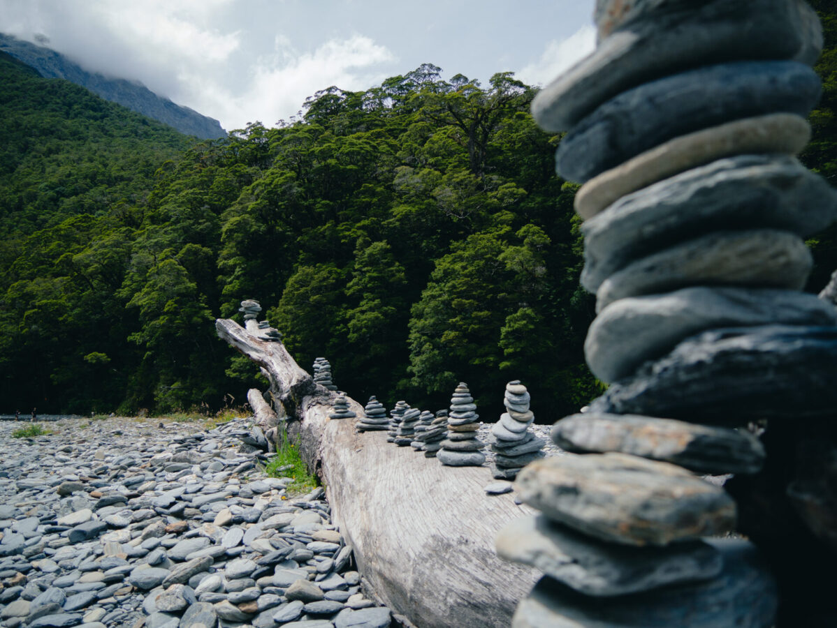 A washed up log topped with cairns in a dry riverbed, found in Mount Aspiring National Park.