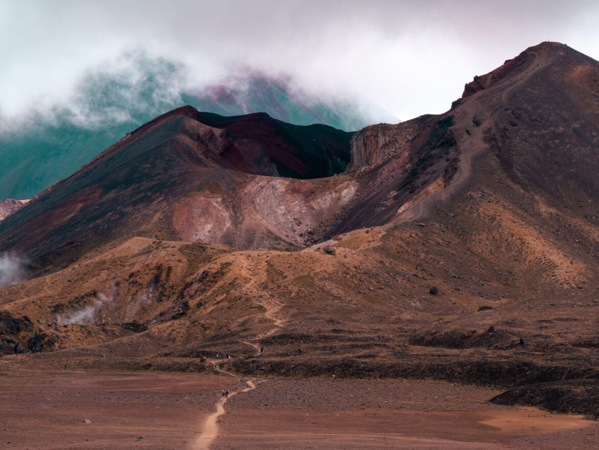 A view of the Red Crater with Mount Ngauruhoe in the background and some hikers on the section of the Tongariro Northern Circuit that overlaps with the Tongariro Alpine Crossing in New Zealand.