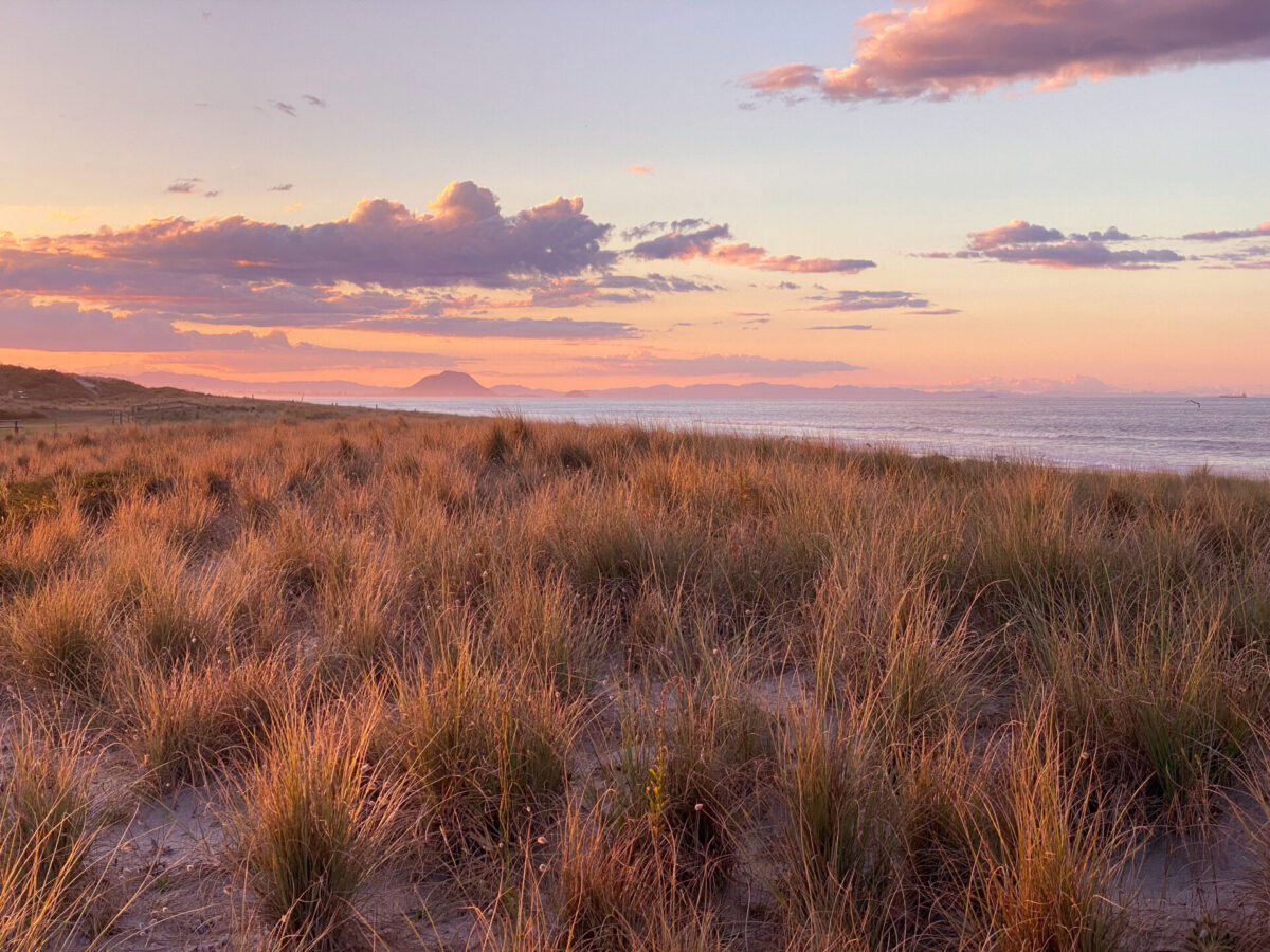 A sunset beach view on Papamoa Beach, New Zealand.