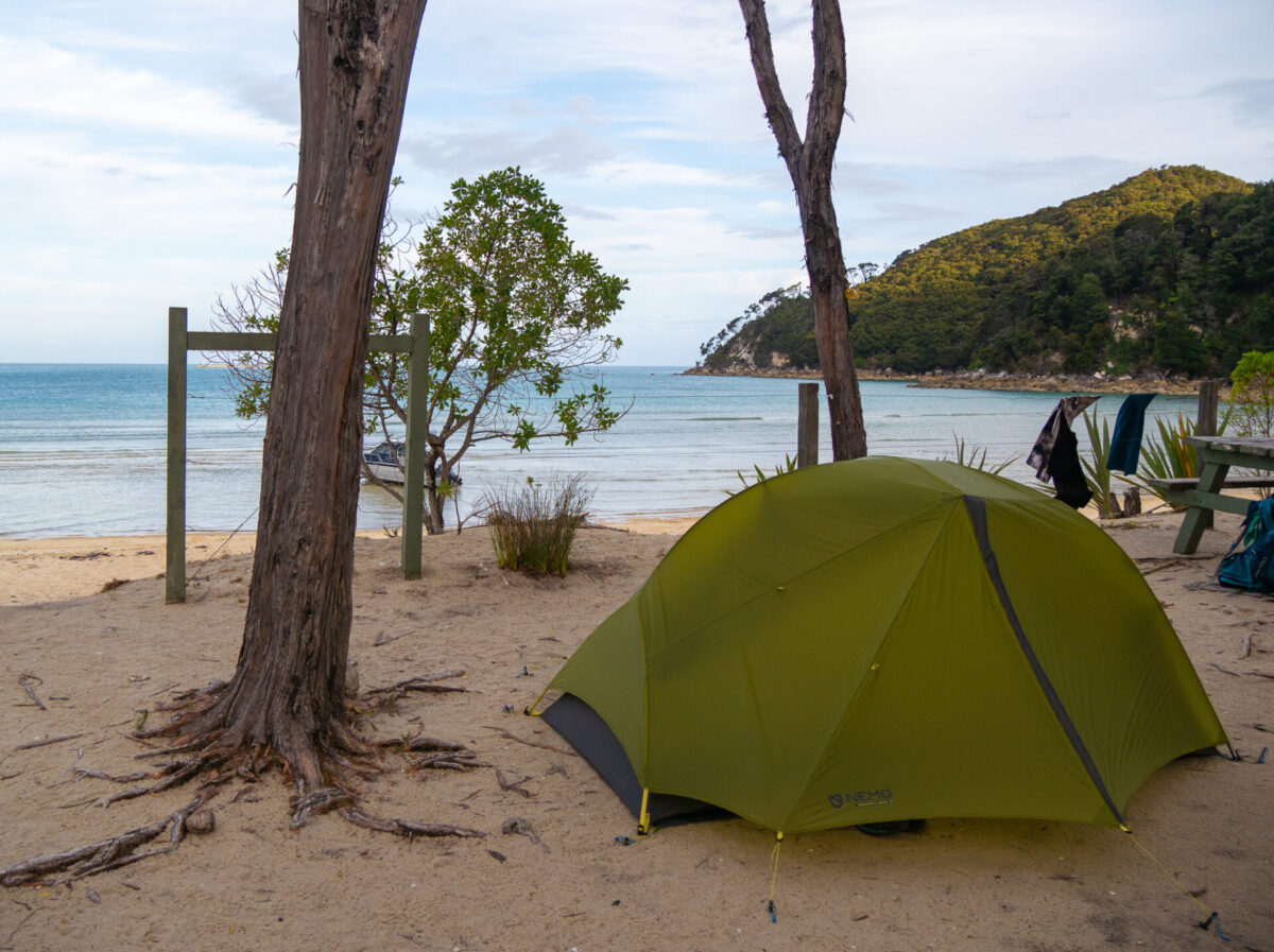A tent pitched on the sand of the Bark Bay campground on New Zealand's Abel Tasman Track.